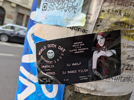 A promotional sticker for the World Goth Day event in Bucharest 2025. The sticker features the date, venue (Emerald Club), and performers (DJ Wwolf, DJ Mandy Filth, and others). The image also contains a stylized illustration of a woman in gothic attire, and promotes music styles like darkwave, gothic rock, EBM, electro-industrial, and agrotech.