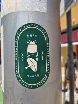 Round green sticker with illustrations of a satellite dish and what looks like a lighthouse or a small tower. The text 'PANTAP' is repeated around the edge, with 'MEPA' at the top and 'NYXTA' at the bottom. 