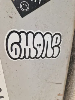 Black and white sticker with the word GHOST written in a stylized font. There are small drips under the text, and the letters are bold and outlined. The background is white.