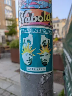 Street sticker The sticker, predominantly teal blue, features two stylized male faces positioned at the bottom. Each face has a jagged, yellow-orange starburst graphic radiating from their head, suggesting an explosion of thought or ideas. Above the left face, a gloved hand holds a spiky, round object, possibly a grenade or a mind-bomb. The left face has an open mouth and wide eyes, appearing surprised or mid-expression. Above the right face, a hand holds a circular object that appears to be a seal or a symbol, with faint text 'SÄKRA FRAMTIDEN' visible on it. The right face has a beard and a more serious or contemplative expression. At the top of the sticker, the text 'GATAS PARLAMENT' is written in bold, white letters, and at the bottom, 'EPIKRISE.' is written in a more subtle, typewritten font.