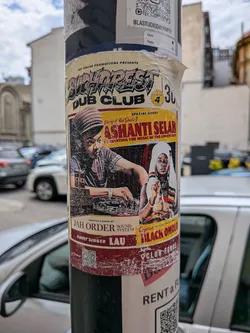Street sticker A rectangular, vintage-style event flyer sticker featuring illustrations of dub artists Ashanti Selah and Empress Black Omolo. It uses a warm color palette of yellow, red, and black, with detailed event typography.