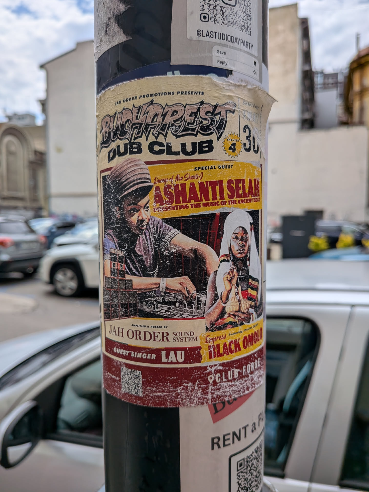 A rectangular, vintage-style event flyer sticker featuring illustrations of dub artists Ashanti Selah and Empress Black Omolo. It uses a warm color palette of yellow, red, and black, with detailed event typography.