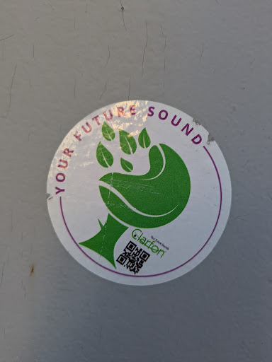 A round, white sticker with a stylized green hand/paw design with leaf-like fingers. The sticker reads "YOUR FUTURE SOUND" around the top circumference. Below the hand graphic, the name "Clarføn" is printed in small black text above a QR code.