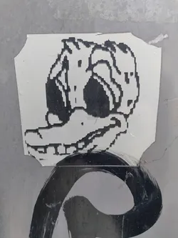 A sticker featuring a pixel art rendition of a duck. The duck is depicted in black and white, with a slightly distorted and mischievous expression.