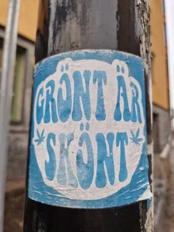 Street sticker A blue and white sticker with the text "Grönt är skönt" (Swedish for "Green is nice") in a retro-style font.  The sticker features two stylized cannabis leaves.