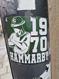 Street sticker A green and white sticker featuring a stylized illustration of a person in a helmet with arms crossed, along with the numbers "1970" and the word "HAMMARBY".