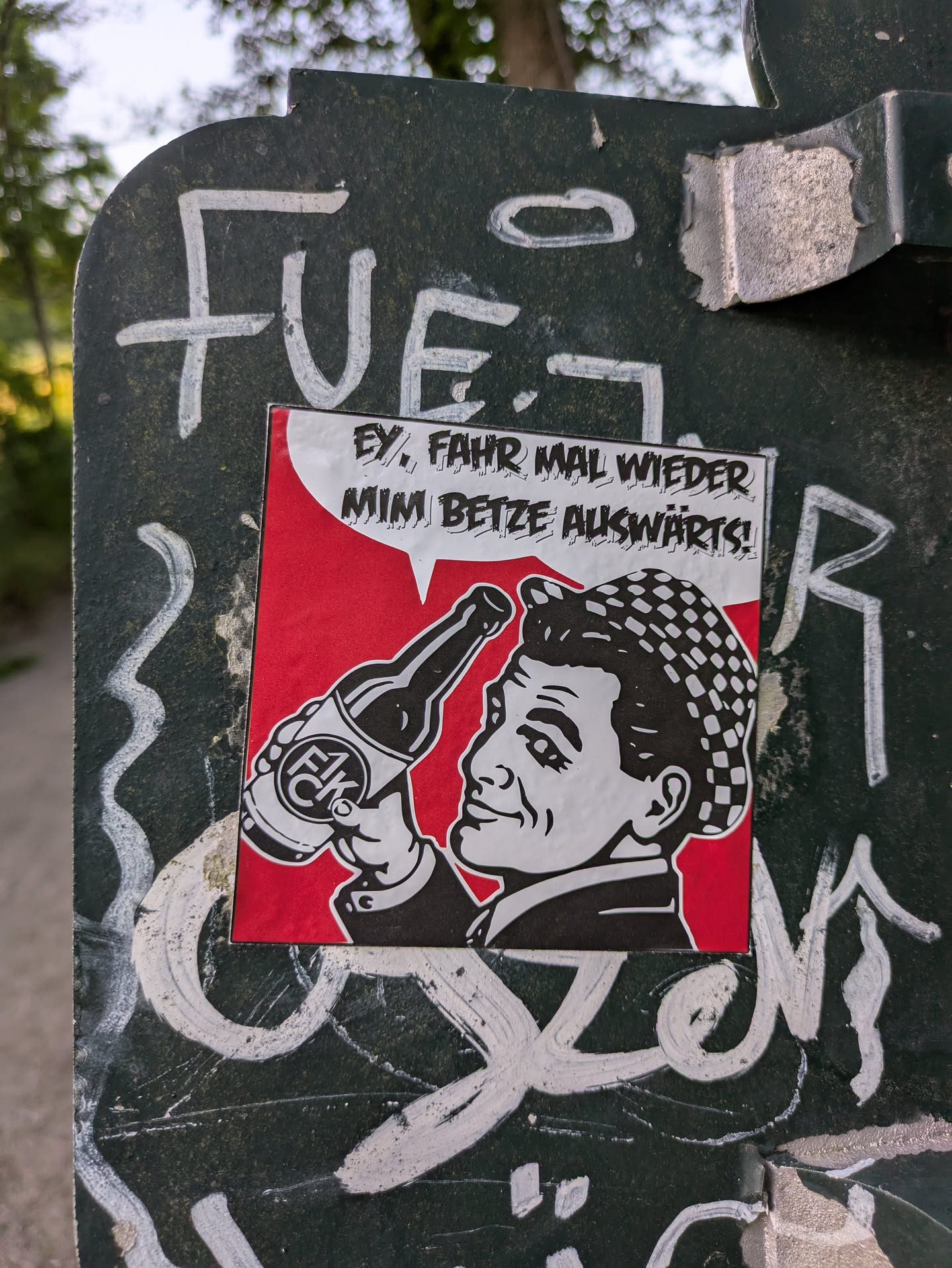 Street sticker The sticker features a cartoonish man holding a bottle. The background is red, and the text in a speech bubble reads 'Ey, Fahr mal wieder mim Betze auswärts!'.