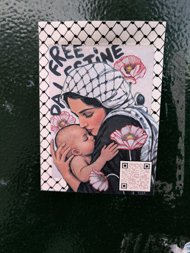 Street sticker This sticker features an illustration of a woman wearing a keffiyeh, holding a baby, surrounded by red and white poppies. It is framed by a keffiyeh pattern. The sticker also says 'Free Palestine'. There's a QR code at the bottom right.