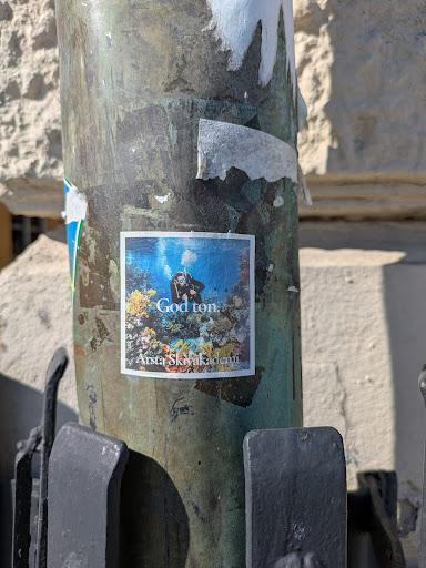 This sticker shows a scuba diver swimming underwater among coral reefs. The text "God ton" and "Arsta Skivakademi" are also printed on the sticker.