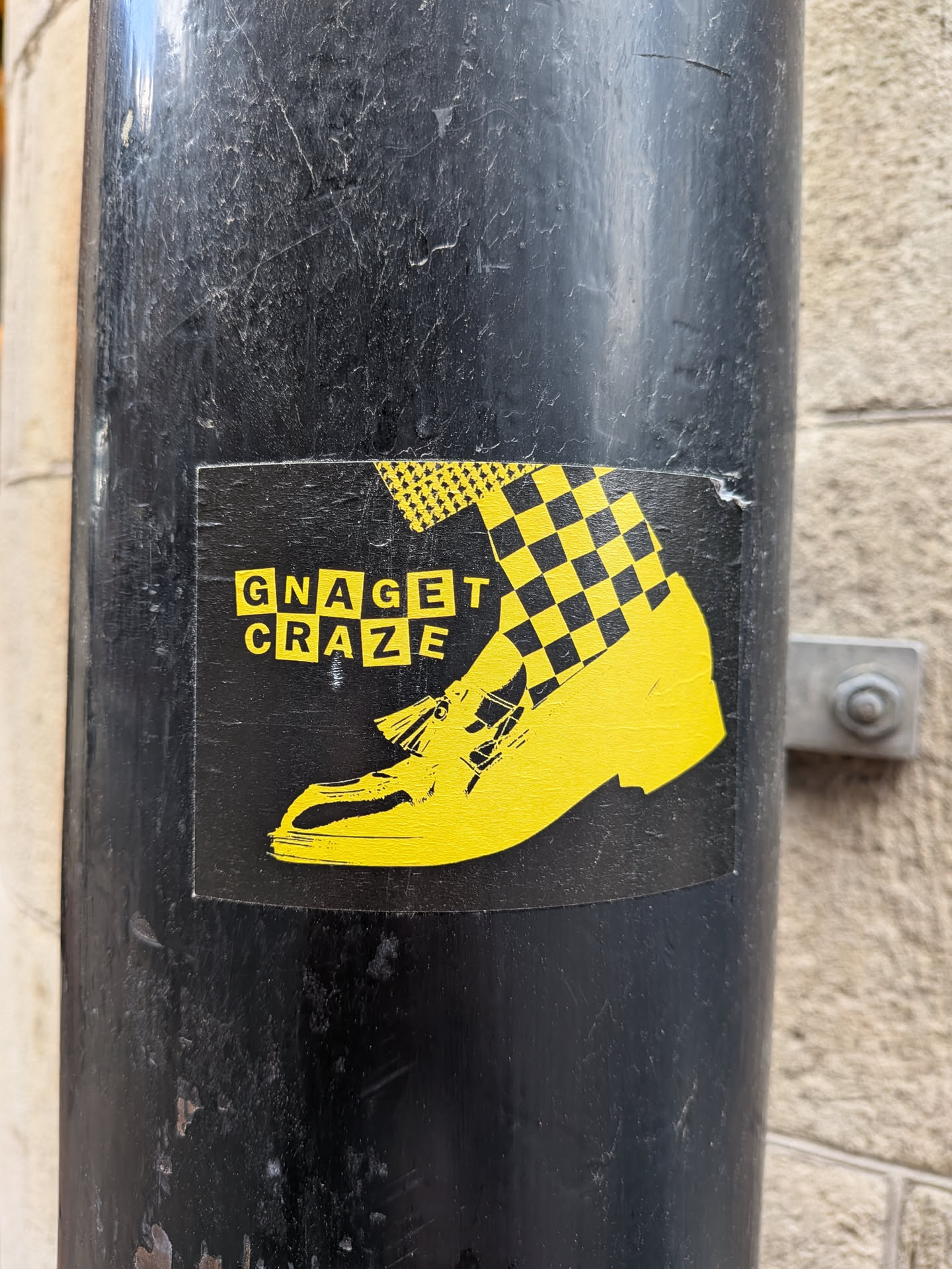 A rectangular black sticker depicting a yellow graphic of a foot wearing a tasseled loafer, checkered socks, and houndstooth trousers. The text 'GNAGET CRAZE' is displayed in blocky yellow letters on the left.