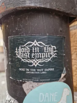 Street sticker A sticker for Void in the Vast Empire, a distribution label.  The sticker features a dark background with the label's name in a stylized, metal-style font.  Social media links for Facebook, YouTube, and Bandcamp are included.