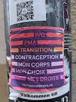 Street sticker A sticker advocating for women's rights, featuring the words IVG (Interruption Volontaire de Grossesse), PMA (Procréation Médicalement Assistée), Transition, Contraception, Mon corps (My body), Mon choix (My choice), and Mes droits (My rights) in French. A QR code is present, likely linking to a related website or resource. The sticker uses a color scheme of purple, pink, orange, and red to create a visually impactful design. It seems to be from an organization called "ToutesDesFemmes".