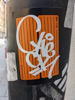 A sticker featuring stylized graffiti text that says "Cafe Gy" in white on an orange and black background.  The sticker also has small text that says "SBA LTS" and "STOCKHOLM".