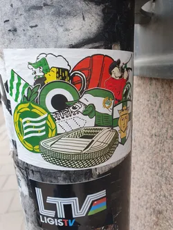 This sticker features a vibrant collection of images related to Lithuanian football, including a stadium, players, flags, beer, and other cultural symbols. The style is reminiscent of vintage sports memorabilia or propaganda posters.