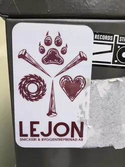 Street sticker A maroon and white sticker with a paw print in the center, surrounded by nails, a circular saw blade, and a heart. The text 'LEJON Snickeri & Byggentreprenad AB' is written below the design.