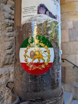 Street sticker A round sticker displaying the Iranian Lion and Sun symbol over a green, white, and red tricolor background. The golden lion holds a sword with a rising sun behind it, enclosed in a golden wreath.