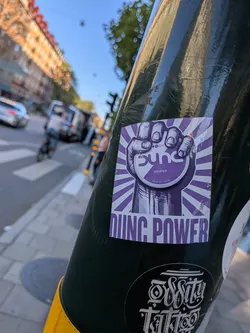 Street sticker A square purple and white sticker depicting a fist holding a circular can labeled 'sync POWER'. Purple rays radiate from the center, with the bold text 'DIING POWER' at the bottom.