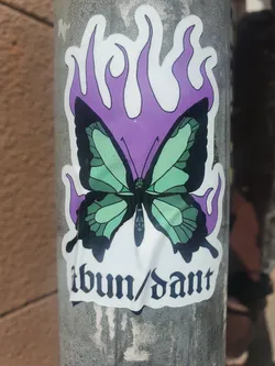 Street sticker A sticker featuring a butterfly engulfed in purple flames. The word Abundant is written in a gothic-style font at the bottom. 