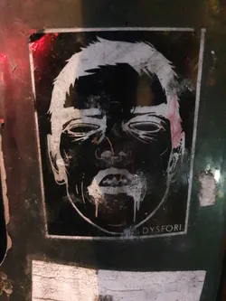 Street sticker The sticker shows a detailed drawing of a man's face in a black and white style. The style is reminiscent of woodcut prints. The word DYSPHORI is visible at the bottom right corner of the sticker.