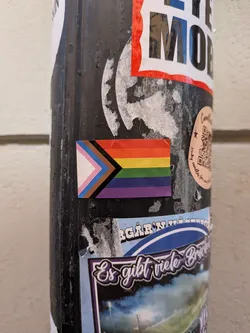 A rectangular sticker of the Progress Pride Flag, featuring a rainbow pattern on the right and a multi-colored chevron on the left.