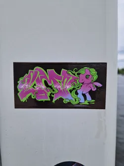 Street sticker A sticker featuring a My Little Pony character incorporated into a graffiti-style design. The pony is pink and purple with green hair, set against a backdrop of vibrant graffiti lettering.