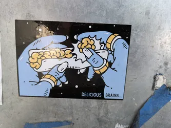 Street sticker The sticker shows two light blue hands, each adorned with gold rings, preparing a brain-filled taco. The background is black with white dots, resembling space. The text at the bottom reads 'DELICIOUS BRAINS...'.