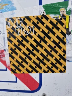 Street sticker This sticker features the letters AIK and the number 1891 in a bold, sans-serif font.  The background is a repeating pattern of diagonal black and yellow stripes, with small, stylized black shapes scattered throughout.  The color scheme is reminiscent of caution tape or warning signs.