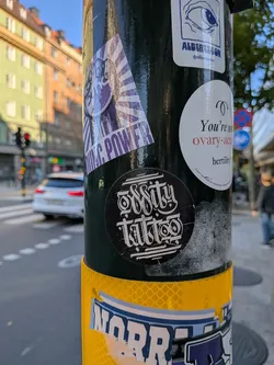 Street sticker A circular black sticker featuring the words 'Oddity Tattoo' in stylized white gothic calligraphy, framed by horizontal lines.