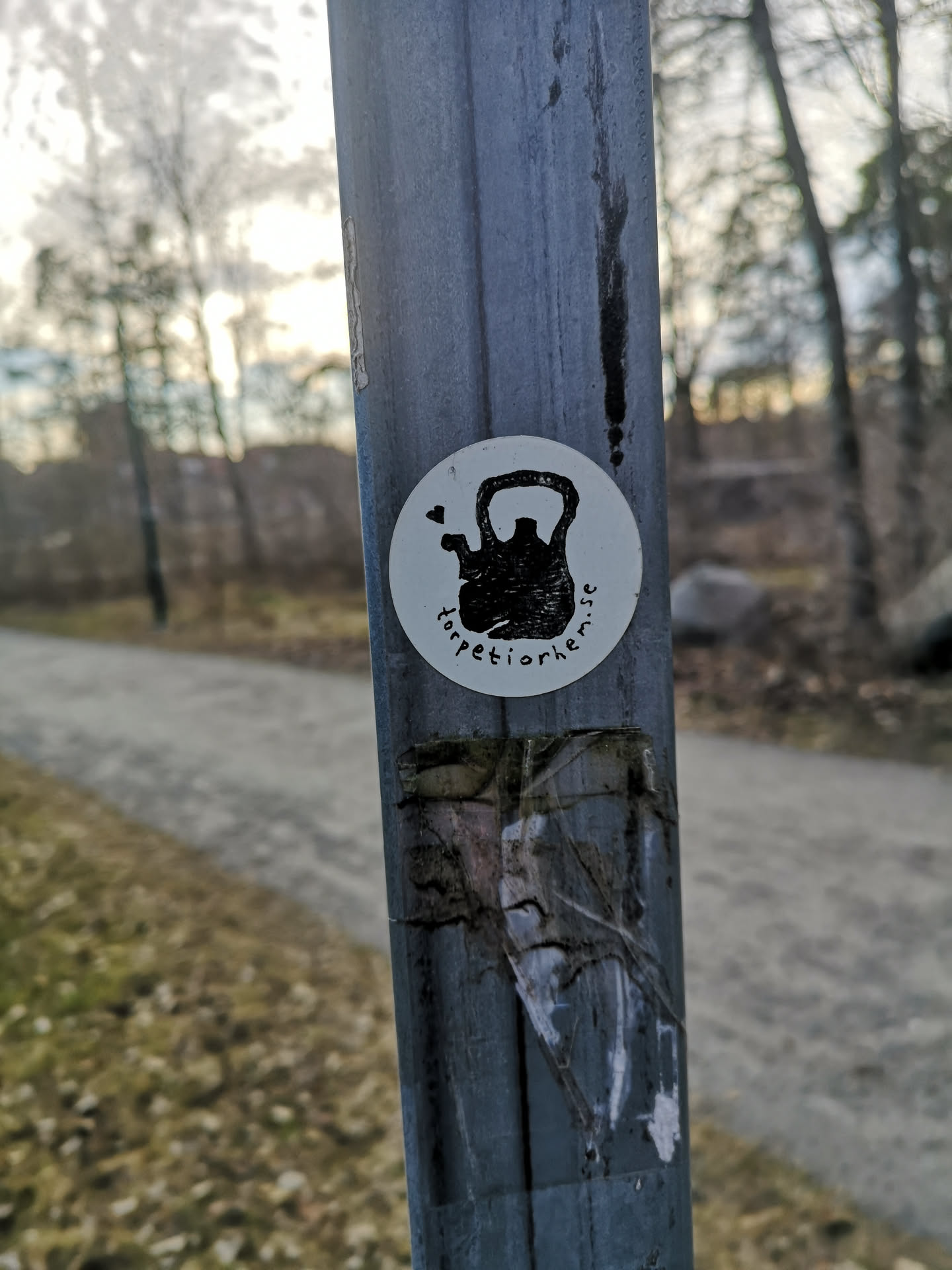 A circular sticker with a white background featuring a black, stylized illustration of a kettlebell. A small black heart shape is depicted above and to the left of the kettlebell, suggesting steam or affection. The text "torpetiorhem.se" is written in black, following the curve of the bottom edge of the sticker.