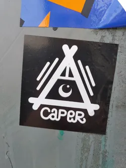 Street sticker Black and white sticker with a logo that resembles a stylized tent or A-frame structure with a crescent moon inside. The word "CAPER" is written in a stylized font below the logo.