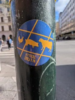 Street sticker Circular blue sticker with yellow grid lines overlaying silhouettes of a chicken, pig, and cow. Features the yellow text '#TOTAL INSYN' at the bottom.