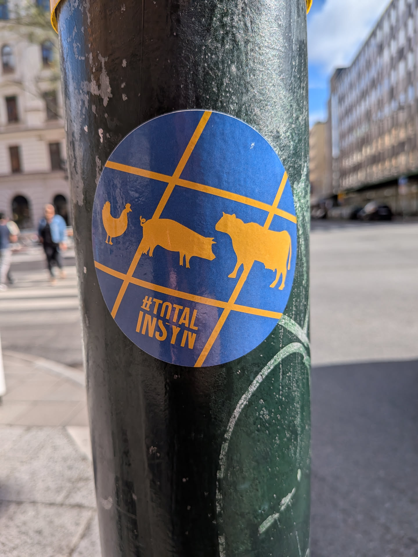 Circular blue sticker with yellow grid lines overlaying silhouettes of a chicken, pig, and cow. Features the yellow text '#TOTAL INSYN' at the bottom.