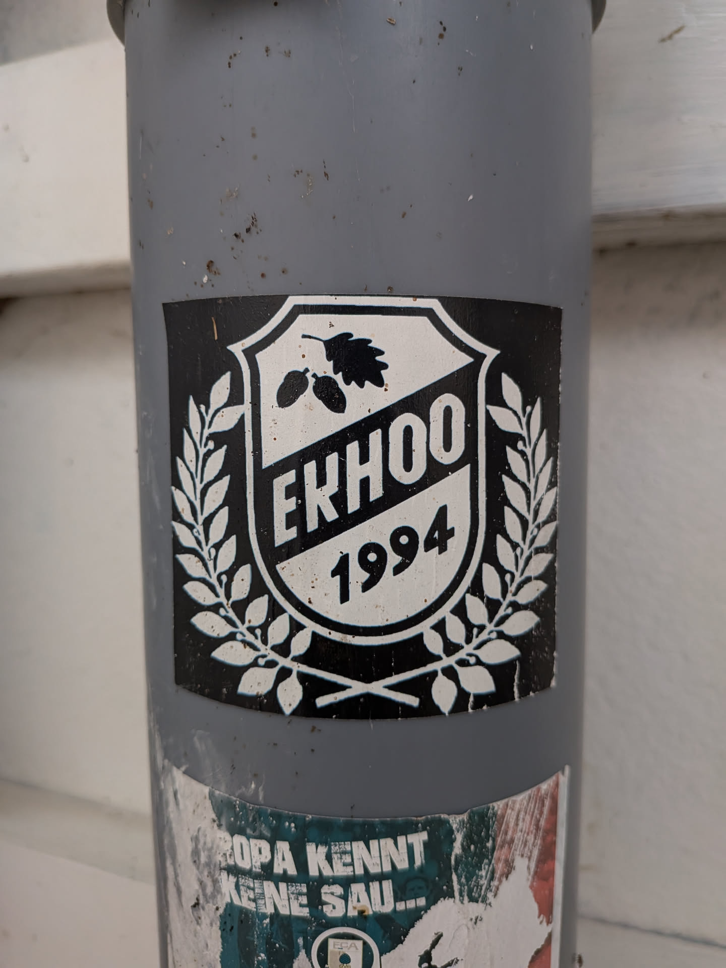 A square black sticker displaying a white shield emblem. The shield contains an oak leaf with acorns, the text 'EKHOO' on a diagonal band, and the year '1994'. A white laurel wreath surrounds the shield.