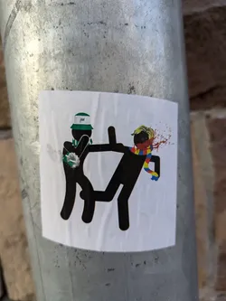 Street sticker The sticker shows a simple, yet violent, scene between two stick figures. One is clearly the attacker, dressed in a bucket hat, while the other is the victim, bleeding from a head injury. The style is minimalistic, relying on bold black lines and limited color.