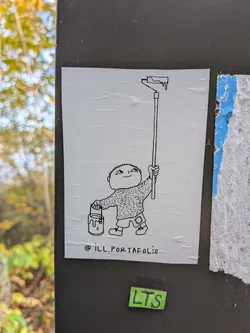 Street sticker The sticker features a simple, hand-drawn black and white illustration on a textured white background. In the center, a small, round-headed character with a wide smile and a slightly mischievous expression holds a paint bucket in its left hand and a long paint roller in its right. The paint roller has a dripping effect at the top, suggesting it's loaded with paint. The character wears a fuzzy sweater and shorts with a patch on one knee. Below the illustration, the text '@ill.PORTAFOLIO' is written in a simple, lowercase font.