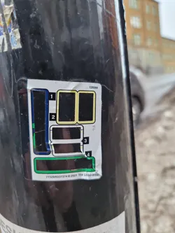 A sticker featuring a diagram, likely showing a map or instructions, with numbers 1-4 indicating different sections.  The text at the bottom includes a number sequence and copyright information for The LEGO Group in 2021. The sticker is affixed to what appears to be a dark-colored pole or post.