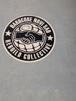 Street sticker A round black and white sticker featuring a handshake icon over a globe grid, enclosed by a circular border with the text 'HARDCORE NOVI SAD REBUILD COLLECTIVE' and two stars.