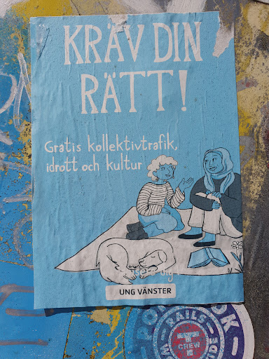 Street sticker A light blue sticker with illustration of two women sitting with two dogs and a book. The text on the sticker says "KRAV DIN RÄTT!" which translates to "Demand your rights!" in English. Below it says "Gratis kollektivtrafik, idrott och kultur", which means "Free public transport, sports and culture". At the bottom it has the logo "Ung Vänster", which translates to "Young Left".