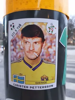 A retro-style sticker featuring Christer Pettersson, a former Swedish footballer. The sticker is reminiscent of classic Panini trading cards, with a portrait of Pettersson in his national team jersey.  The text 'ETT X TVÅ' is visible in the top left corner, and 'SVERIGE' (Swedish for Sweden) is printed on the bottom part of the sticker.
