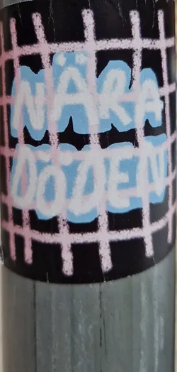 Street sticker A sticker featuring the text "Nara Dvolen" in light blue and pink lettering on a black background with a pink grid pattern. The text appears to be stylized graffiti or hand-painted.