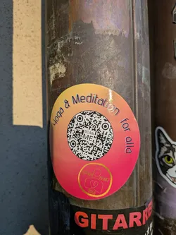 Street sticker A circular sticker featuring a vibrant gradient background, transitioning from a light orange-yellow at the top to a rich magenta-pink at the bottom. A prominent black and white QR code occupies the center, with the text 'SCAN ME' clearly visible within it. Arching along the top edge of the sticker is the text 'Yoga & Meditation' in a dark, slightly shadowed font. Along the bottom edge, curving upwards, is 'for alla'. At the very bottom center, within the pink area, is a small golden circular logo containing the text 'GOLDEN HEART YOGA' and a stylized icon depicting a person in a meditative pose with a heart shape.