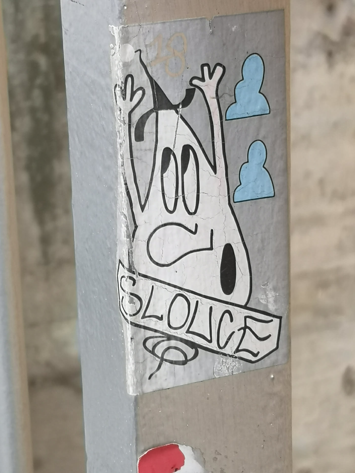 The sticker features a stylized, somewhat amorphous white character with a thick black outline, resembling a ghost or a blob-like figure. It has large, oval-shaped eyes looking upwards and a small, downturned mouth, conveying a surprised or distressed expression. Two arms are raised with three-fingered hands. A small black tear-drop shape is visible on its lower right side. To the right of the character, there are two light blue, cloud-like or abstract head-like shapes, also with black outlines. Below the character, a banner-like element contains the text "SLOLICE" in bold, blocky, black capital letters. The sticker itself has a light grey background and shows significant signs of wear, cracking, and peeling, indicating its age and exposure to elements. A faint, light brown '18' is barely visible above the character's head.