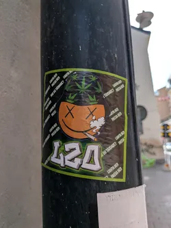 Square sticker with a green border showing an orange smiley face with 'X' eyes smoking a joint. The character wears a black bucket hat decorated with green cannabis leaves. Below is the number '420' in stylized block letters. The background features repeating Swedish text.