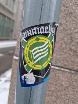 Street sticker A sticker featuring the logo of Hammarby IF, a Swedish football club. The logo is a green and yellow crest with a flag and laurel wreath.  The text "Hammarby" is written above the crest in a gothic-style font.