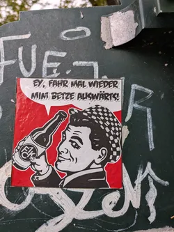 Street sticker The sticker is square-shaped with a red background. It depicts a man in profile, wearing a checkered cap and a suit jacket. He is holding a beer bottle with a label that reads 'F1CK' in a circular design. A speech bubble above his head contains text. The artwork is in a black and white, graphic style with bold outlines.