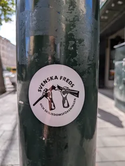 Street sticker A circular white sticker featuring a black graphic of two hands breaking a rifle in half. The Swedish text 'SVENSKA FREDS OCH SKILJEDOMSFÖRENINGEN' is printed in black, curving along the top and bottom borders.