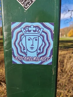 Street sticker A sticker featuring a stylized illustration of a queen wearing a crown, set against a swirling, psychedelic background. The text 'STOCKHOLMSLAGET' is visible at the bottom.