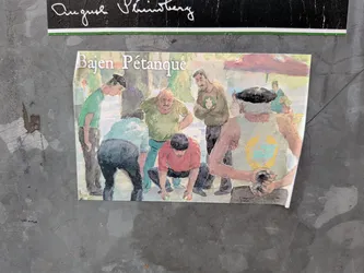 Street sticker A rectangular sticker featuring a watercolor-style painting of a group of men playing pétanque outdoors. The text 'Bajen Pétanque' is printed in white serif font at the top left. The scene depicts several men in casual clothing, some wearing green and white colors associated with the Swedish club Hammarby ('Bajen'). One man in a red shirt is crouching to measure or play, while others watch intently. In the foreground, a man wearing a dark beret and a light green tank top holds a pétanque ball. The background shows a park-like setting with trees and a red parasol.