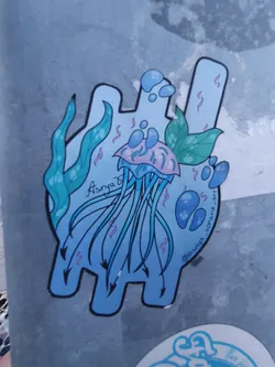 Street sticker A cute jellyfish sticker with seaweed and bubbles in light blue and pink colors. The sticker is in a unique shape, and has the artist's name, Asrya, written on it. There is also an instagram handle @asrya_vorona_art on the sticker.