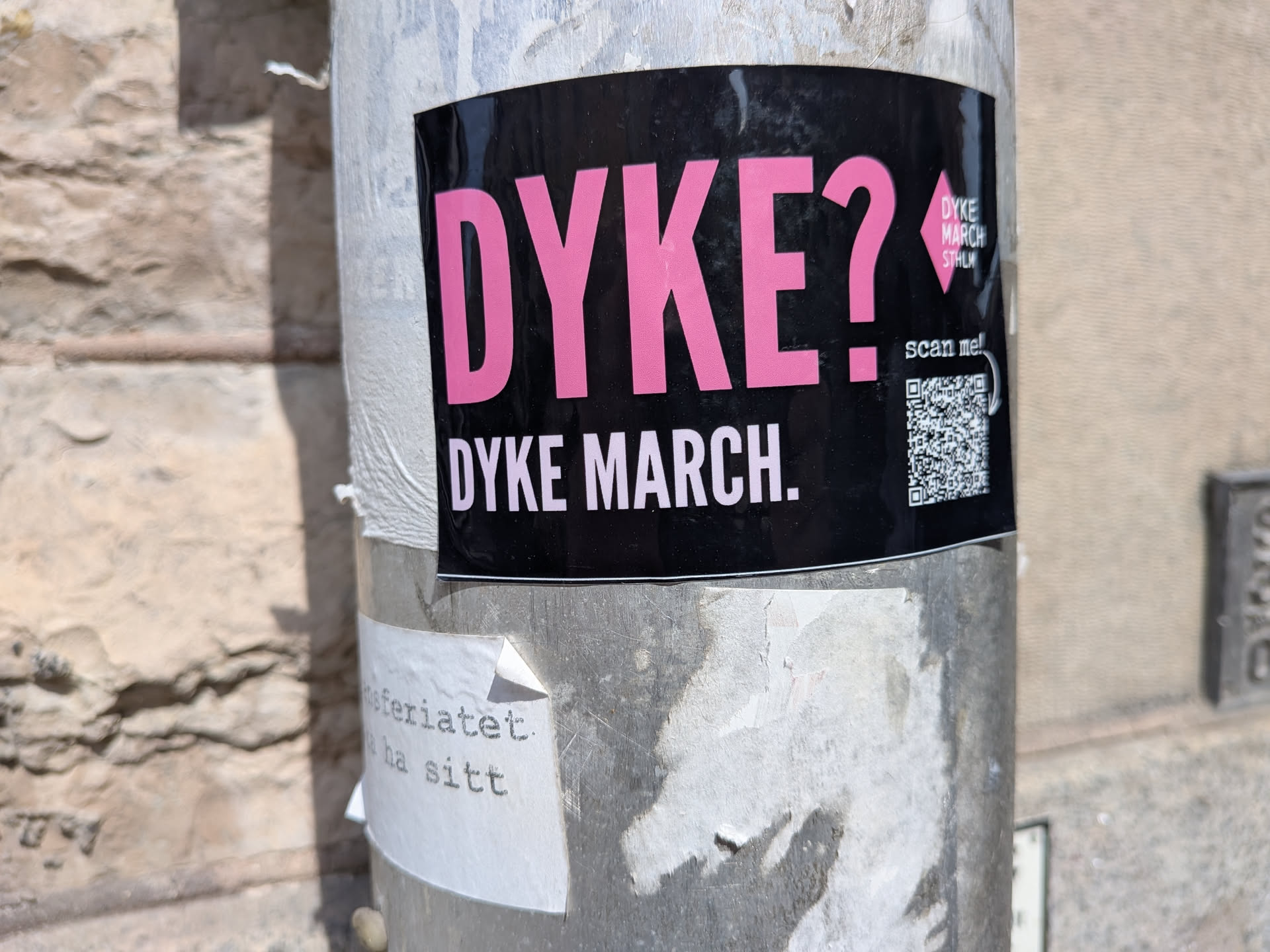A black rectangular sticker featuring bold pink 'DYKE?' text, white 'DYKE MARCH.' text, a pink diamond logo, and a QR code on the right.